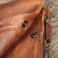 Close-up of snap buttons and zipper on a handmade brown leather wallet