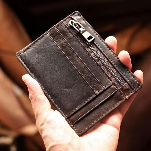 Back of ultra thin dark brown leather billfold wallet with zip pocket, held in hand