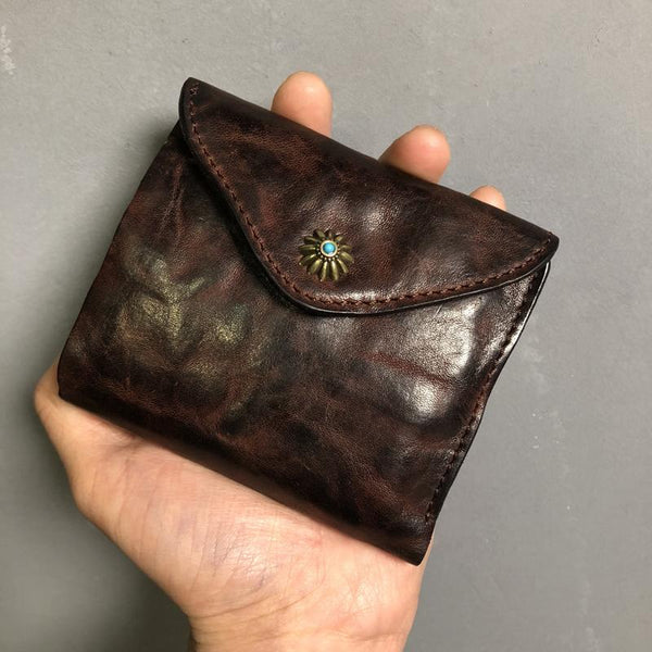 Back of vintage coffee envelope style leather billfold wallet with turquoise concho, held in hand