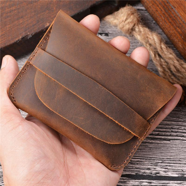 Hand holding vintage brown distressed leather coin holder with fold-over flap