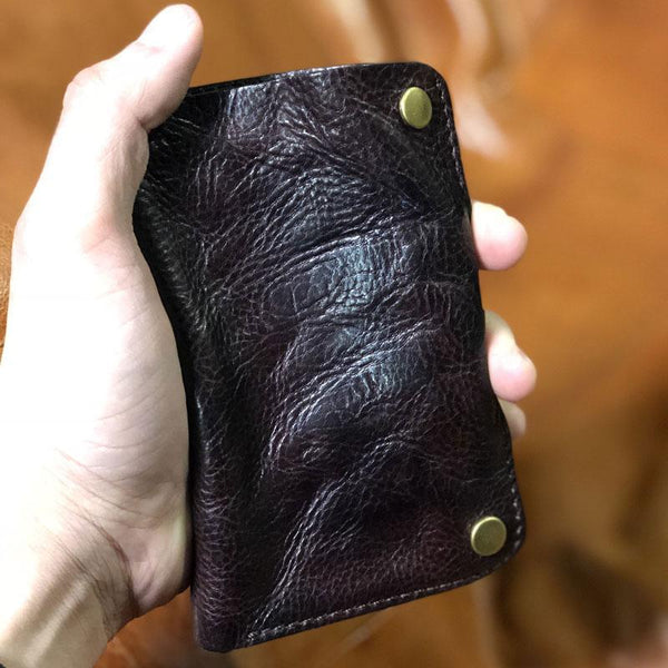 Handmade textured full-grain leather billfold wallet held in hand, coffee with brass rivets