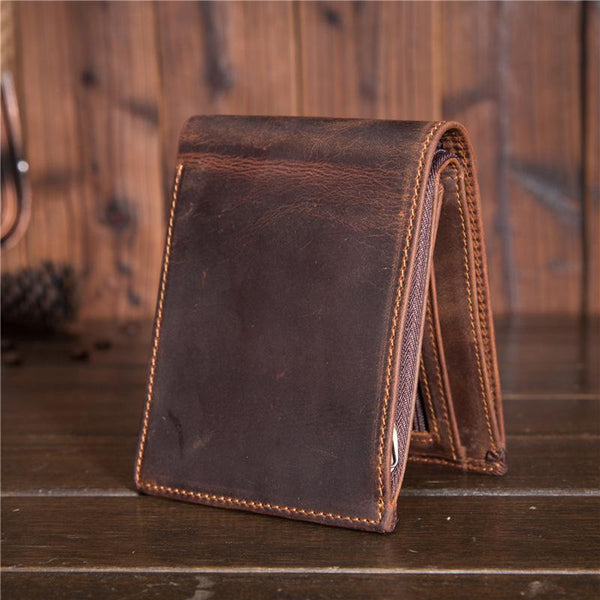 Brown distressed leather billfold wallet standing folded on wooden surface