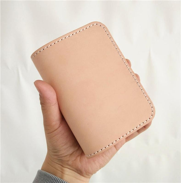 Hand holding natural beige vegetable tanned leather billfold biker wallet with white stitching