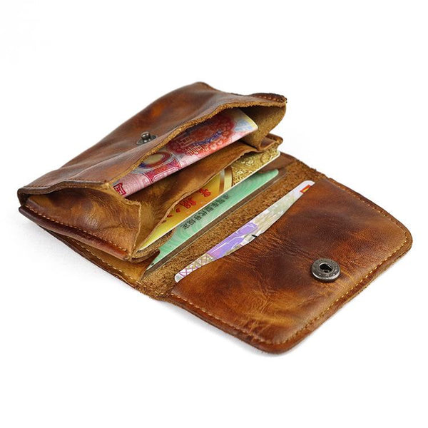 Open vintage brown leather card wallet with snap flap showing cards and cash inside