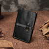 Vintage black leather vertical billfold wallet with wrap strap closure and white stitching