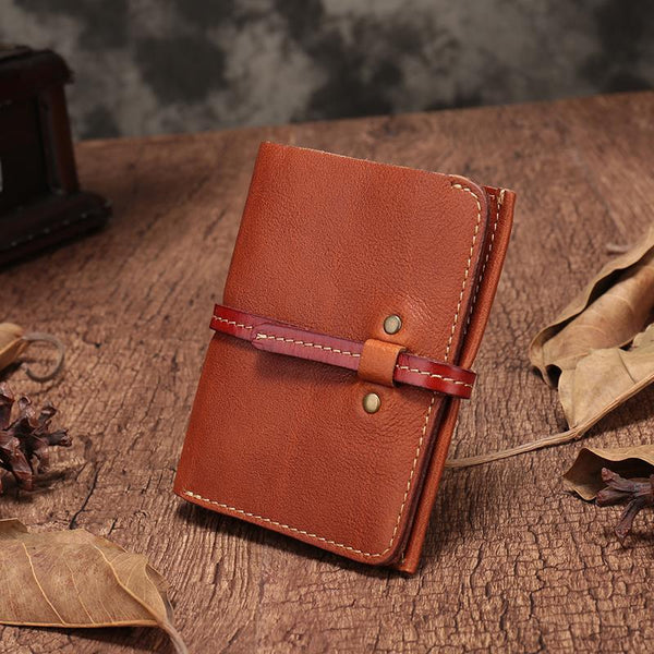 Vintage brown leather vertical billfold wallet with wrap strap closure and white stitching